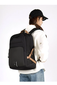 Side view of large black commuter backpack with brown handles and waterproof nylon fabric