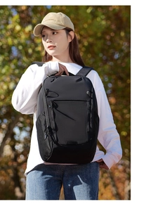 Detail view of durable black multifunctional outdoor backpack worn by a model in autumn