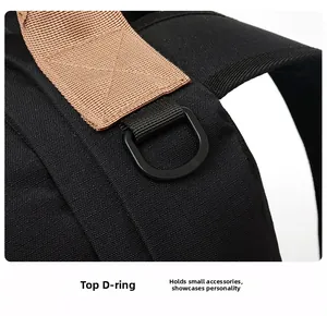 Detail of the black backpack showing the D-ring attachment with brown stitching accents