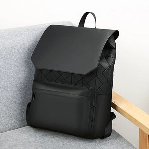 Detail of matte black geometric backpack with triangle mosaic tiles on grey sofa