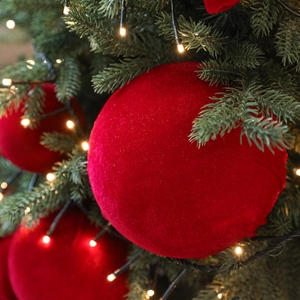 Boule de Noël luxueuse en velours bordeaux sur une branche de sapin illuminée