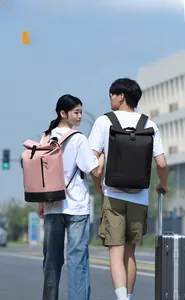 Close-up of pink and black roll-top backpacks with water-resistant fabric and buckle detail