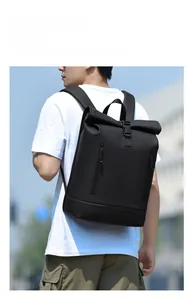 Outdoor model wearing a black roll-top laptop backpack with water-resistant fabric