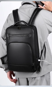 Close-up of black leather business backpack featuring external USB charging port detail