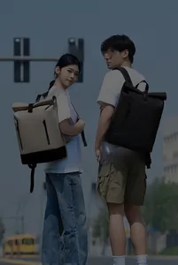 Outdoor shot of beige and black roll-top travel backpacks for 16-inch laptops