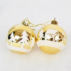 Golden 6cm Christmas balls with glittery snow house patterns and mirror finish on white snow