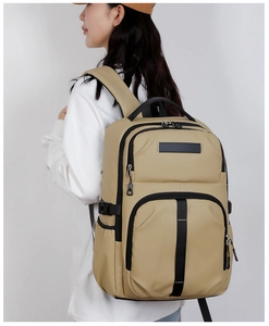 Detail of khaki functional backpack featuring multiple zippered pockets and sturdy top handle