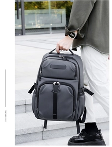 Detail of grey water-resistant backpack with reinforced top handle and multi-zip compartments