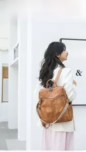 Brown vintage style backpack with braided shoulder strap shown in an outdoor lifestyle setting