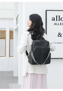 Detailed view of black leather backpack featuring white contrast stitching and woven handles