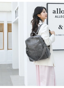 Outdoor shot of a grey casual backpack with woven straps on a woman in white jacket