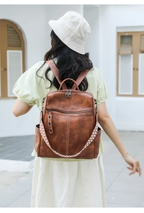 Rear view of brown leather backpack featuring a vintage texture and woven strap detail