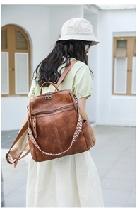 Brown leather backpack featuring a vintage aesthetic with colorful ethnic woven shoulder strap