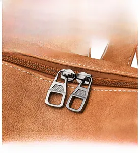 Detail view of brown lychee leather bag featuring a smooth dual metal zipper and white stitching