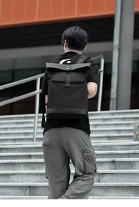 Close-up of black roll-top backpack with metal buckle on waterproof nylon fabric