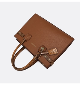 Dettaglio della borsa tote marrone con trama litchi e cinturini in pelle a coccodrillo