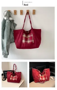 Detail of red canvas tote bag featuring a British plaid pocket and faux leather tag