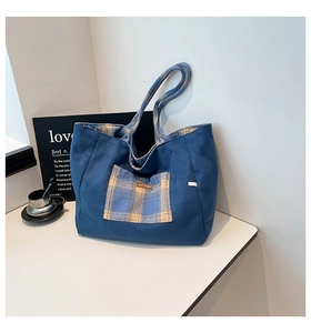 Detail of blue canvas tote bag featuring a yellow plaid pocket and interior lining