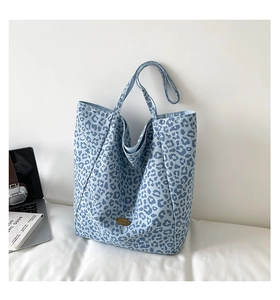 Close-up of blue leopard print canvas tote bag with metal label and long shoulder strap