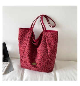 Detail view of large burgundy leopard print canvas tote bag with handmade metal label