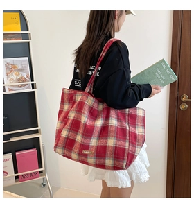 British style red and white plaid wool tote bag worn by a model in a cozy indoor setting