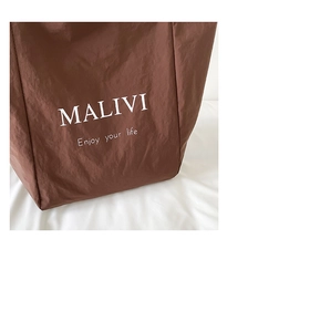 Close-up of brown nylon tote bag with MALIVI print on a white fabric background