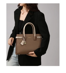 Dettaglio della borsa tote in pelle marrone con manici a motivo coccodrillo e decoro a lucchetto