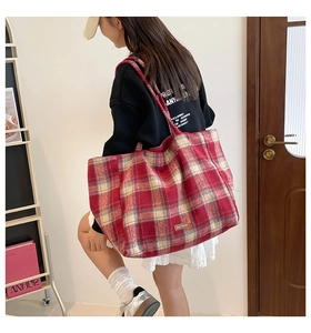 Detail of red and white plaid wool tote bag with leather label and spacious side profile