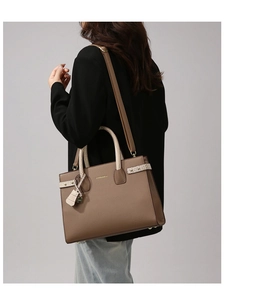 Dettaglio borsa shopper marrone scuro con manici effetto coccodrillo sulla spalla della modella