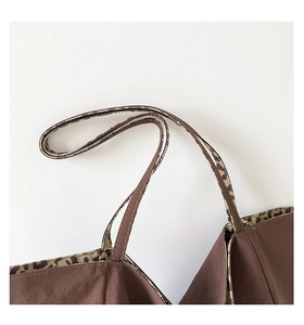 Detail of dark brown tote bag showing leopard print lining and reinforced stitching