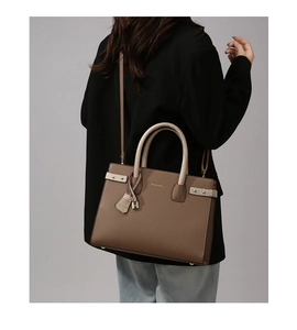 Dettaglio della borsa in pelle marrone con manici cocco beige indossata da modella