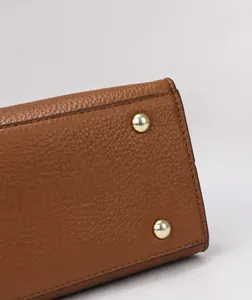 Dettaglio della base della borsa in pelle litchi marrone con piedini dorati