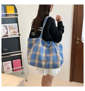 Detail of blue and beige plaid tote bag showing the brown 'our love' leather label