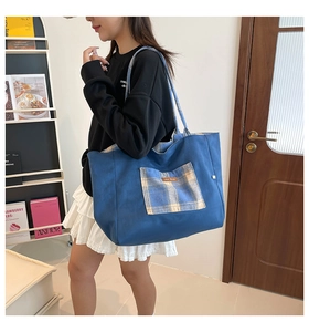 Detail shot of a blue canvas tote bag featuring a checkered pocket and leather patch tag