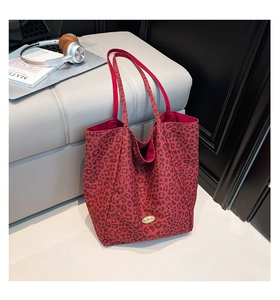 Detail of red leopard print canvas tote bag featuring an oval gold handmade metal plaque