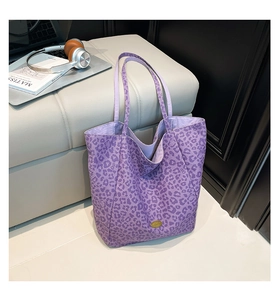 Detail of purple leopard print canvas tote bag with gold logo on a studio set