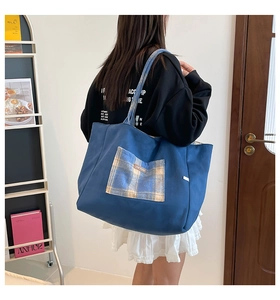 Detail of blue canvas tote bag featuring a yellow plaid front pocket and high capacity