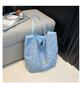 Detail of blue leopard print tote bag with golden metal logo on high quality canvas fabric