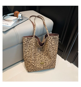 Detailed close-up of a large leopard print tote bag with a gold metal logo on soft canvas
