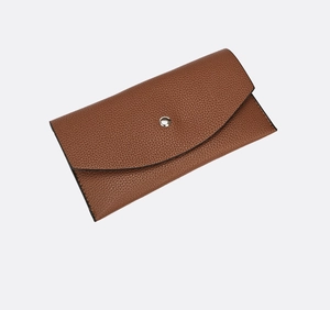 Dettaglio macro della pelle martellata marrone sulla pochette con bottone a scatto