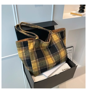 Detail of large check woolen tote bag with long handles inside a black gift box