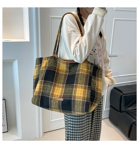 Detail of British style yellow plaid wool tote bag with leather logo patch and long straps