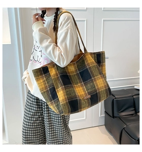 Detail of yellow and black plaid wool tote bag with brand label and long shoulder strap