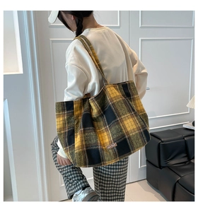 Detail of the yellow and black plaid tote bag showing the textured fabric and brand label