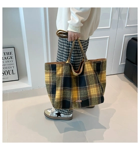 Detail of classic plaid tote bag texture and leather logo patch in vintage autumn style