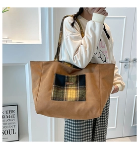 Detail of plaid pocket on brown tote bag with leather tag and vintage handle design
