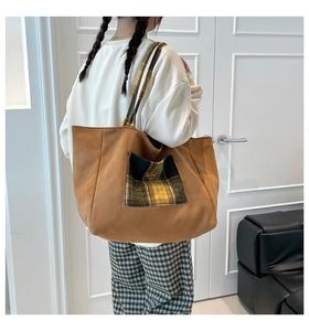 Detail of camel canvas tote bag featuring green plaid pocket and dual handles