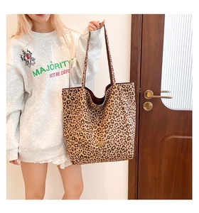 Detailed view of the leopard print tote bag featuring a metallic logo and deep red lining