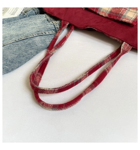 Close-up of the burgundy wool tote bag with classic plaid shoulder straps and pocket