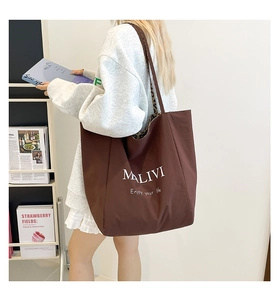 Brown canvas tote bag with leopard print lining shown on model in a cozy library